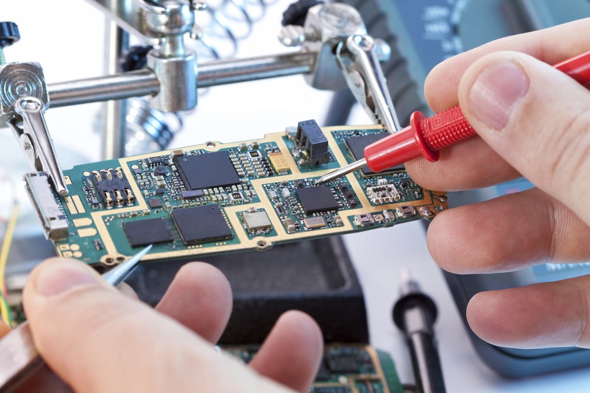 Technician inspecting an electronic circuit board for a repair assessment.